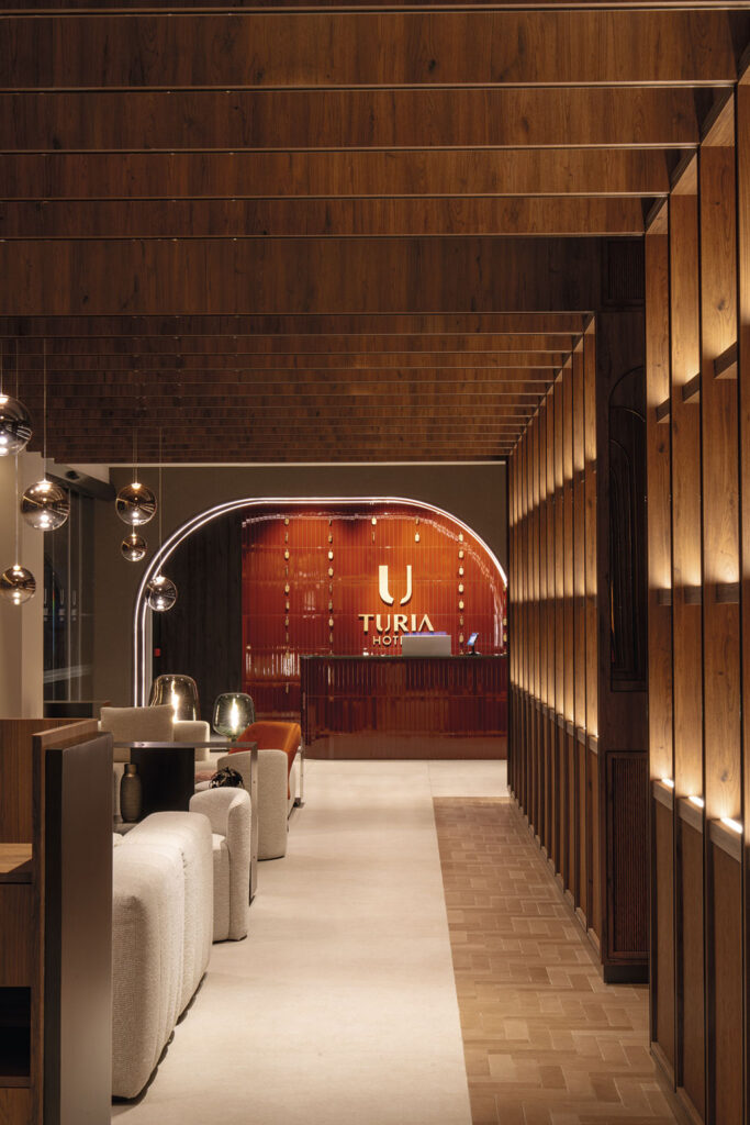 Lobby del Hotel Turia Badajoz con zonas de asiento y vegetación interior.